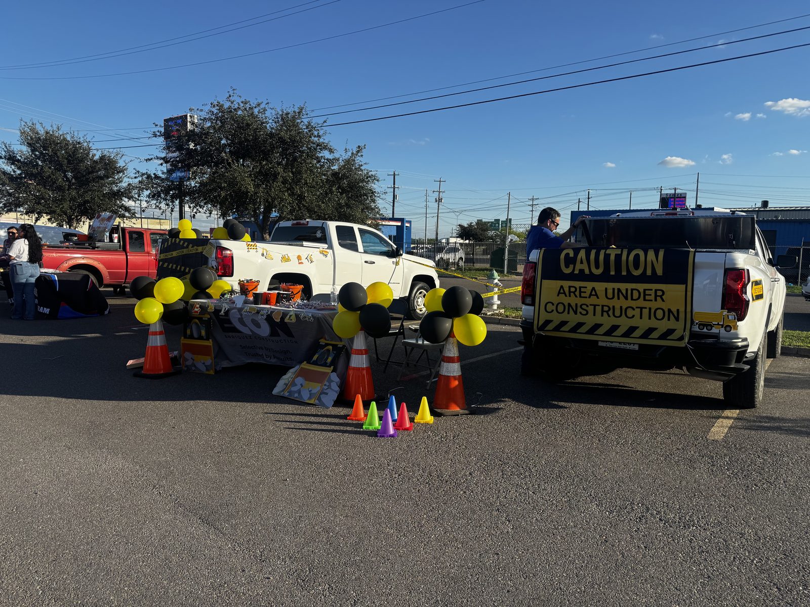 E-CON Group construction-themed Trunk or Treat setup with caution-tape trucks, cones, and balloons in Pharr, TX, Rio Grande Valley
